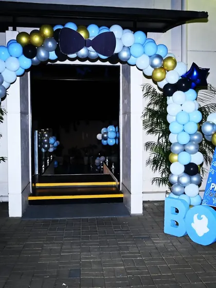 We created an impressive entrance for Prithvi's Boss Baby party with this balloon arch in shades of blue, black, silver, and gold. A custom welcome sign and large "BOSS" letters set the tone for the celebration right from the door.