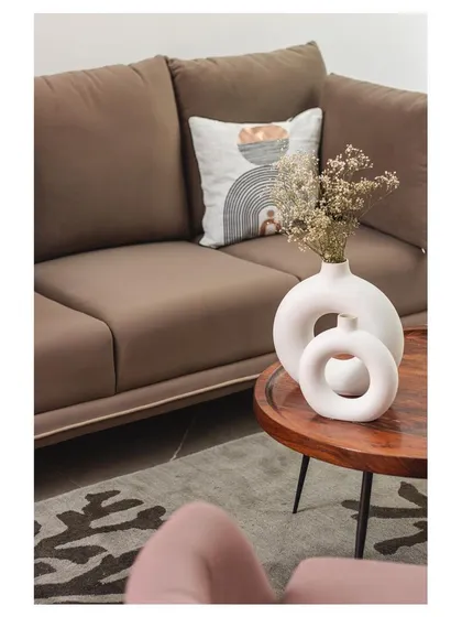 A close-up of the styling details, where modern ceramic vases and a patterned cushion add a touch of artistry to the minimalist sofa.