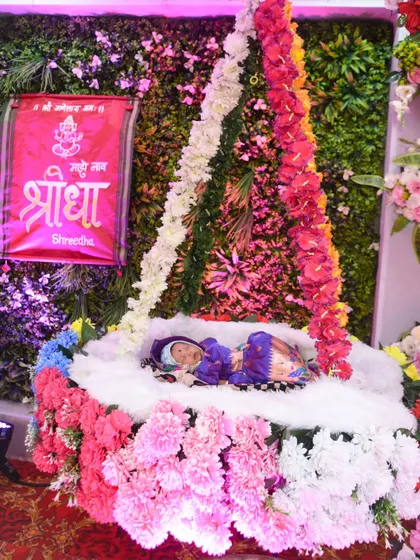 The baby rests in a beautifully decorated floral cradle during the Naamkaran ceremony.
