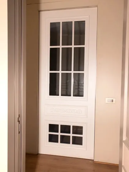 A classic white door with glass panels, ideal for letting natural light into hallways or connecting rooms. The design is timeless and versatile.