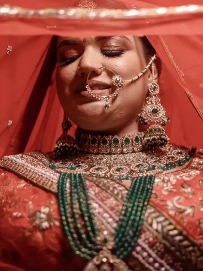A beautiful close-up of a bride, her eyes closed, highlighting her stunning green and red bridal jewelry.