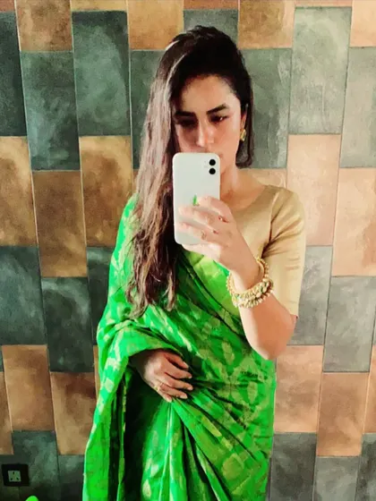 A vibrant green Banarasi silk saree is a wardrobe essential for its rich color and traditional weave. In this mirror selfie, you can see how it drapes beautifully, making it a go-to for any festive celebration.