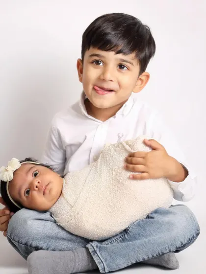 Capturing the real, playful moments is what I do best. A big brother makes a funny face while his alert newborn sister looks on, showing the fun side of sibling photos.