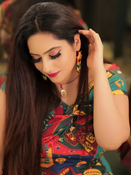 A beautiful portrait of a model in a colorful, modern outfit. The soft lighting and gentle pose highlight her features and the unique pattern of her top.