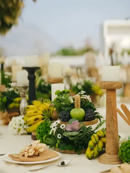 A tablescape from our 'Easy Breezy Brunch', where nature and elegance meet. The centerpiece is a beautiful arrangement of fresh fruits, vegetables, and white flowers, reflecting the event's focus on sustainability and simplicity.