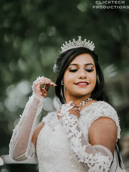 A close-up of the bride adjusting her necklace, highlighting the details of her dress, makeup, and accessories.