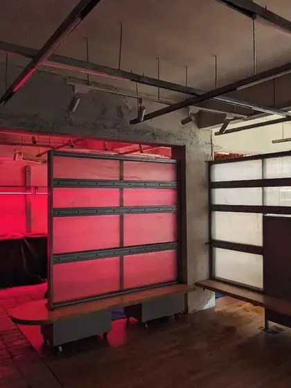 The space during the final stages of construction, with the movable partitions and lighting being tested. The red glow highlights the industrial feel of the exposed ceiling and concrete walls.