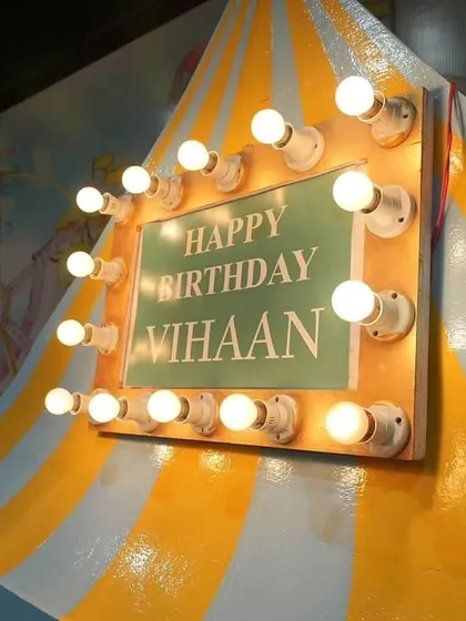 A custom 'Happy Birthday' sign with marquee lights, designed for Vihaan's carnival theme. This small detail adds a touch of classic circus glamour.
