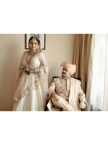 Another angle of the couple's portrait, with the groom seated and the bride standing, creating a dynamic and regal composition.