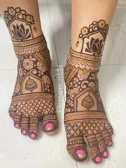 A foot design that truly stands out. The combination of floral patterns, jhumka motifs, and a lotus border creates a rich and detailed look that is perfect for a bride.