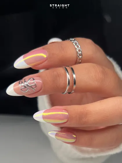 A modern French manicure with an iridescent chrome finish. The classic white tip is updated with a pearly, multi-tonal sheen and a silver chrome accent for a futuristic feel.