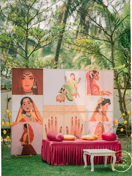 A unique Mehendi seating area with a custom backdrop featuring beautiful illustrations of brides.