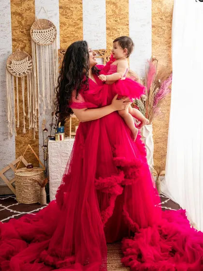 A candid and loving interaction between a mother and her baby girl. The way they look at each other, framed by the flowing red gown, tells a story of pure love.