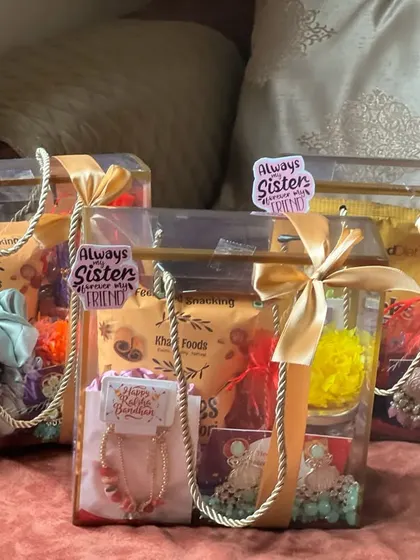 A set of three matching Rakhi gift bags for sisters, each with snacks and a special "Always Sister, Forever Friend" sticker.