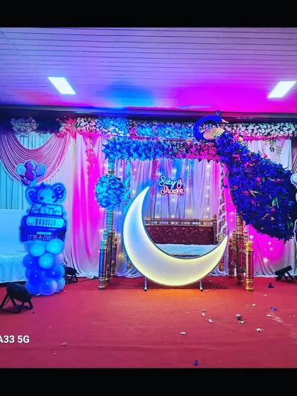 A full view of the peacock-themed baby shower stage, showing the entire setup with pink and blue lighting effects.