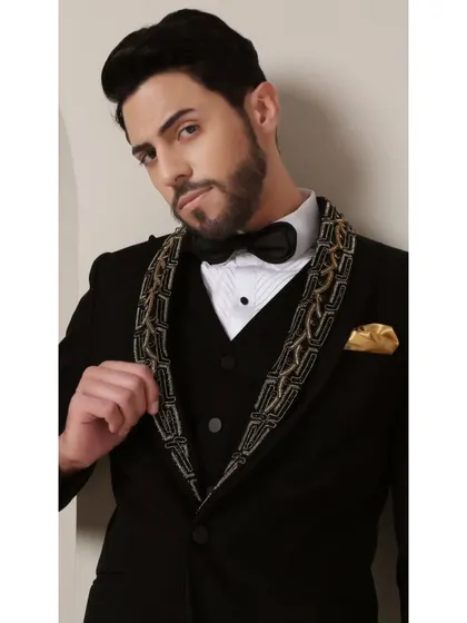 A detailed view of the Gilded Onyx Majesty tuxedo's lapel. The bold black and gold handcrafted pattern creates a symphony of dark and luminous sophistication, making it a true statement of strength and elegance.