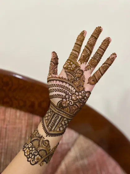 This design for the back of the hand extends up the arm, featuring a lovely mix of leafy vines and traditional Indian mehendi elements.