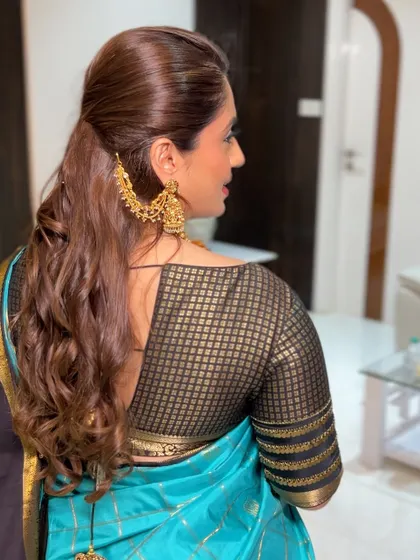 The back view of the modern reception look. The saree is draped to show off the beautiful blouse design, and the hairstyle is both elegant and secure.