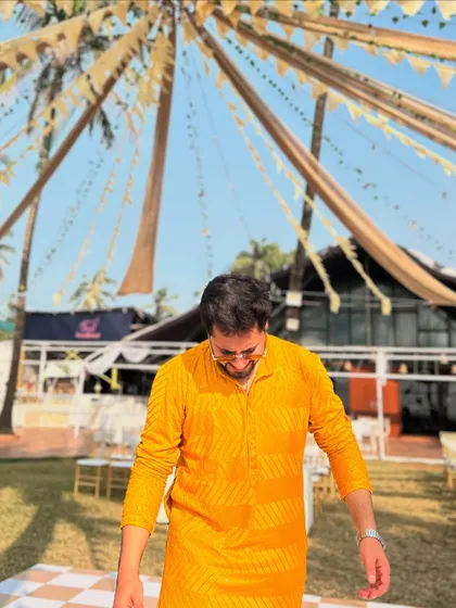 A playful moment captured at a Haldi event, looking down with a smile under the beautiful tent decor.