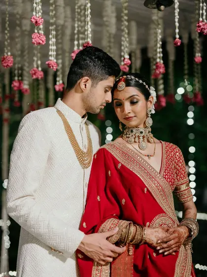 A quiet moment between the couple amidst the wedding rituals. The soft glow of the mandap and the delicate hanging florals create a romantic and intimate setting for these precious memories.