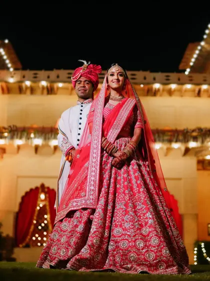 A full-length portrait of the couple at their destination wedding venue, highlighting the intricate details of their beautiful outfits.