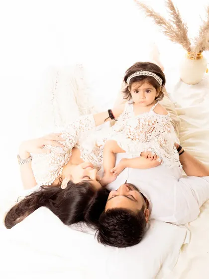 An artistic shot of a family lying down together, with their daughter positioned between them. This perspective offers a unique and intimate view of family connection.