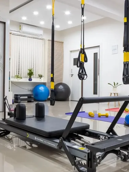 A glimpse into my clean and well-equipped studio. The space is designed to be a calm environment for focused movement, featuring the Pilates Reformer, TRX suspension trainers, and a variety of props to support your practice.