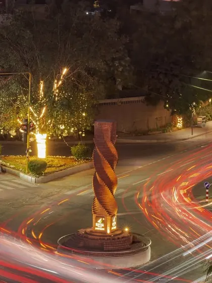 An aerial night view of the junction, with light trails from vehicles swirling around the illuminated Urban Twist sculpture, highlighting its role as a central anchor in the urban landscape.
