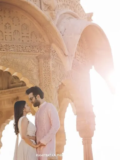 Backlit by the golden desert sun, a couple shares an intimate moment under the carved arches of a Jaisalmer ruin.