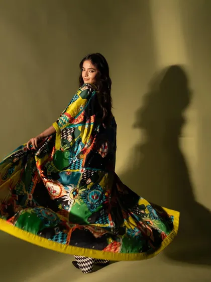 A dynamic shot of Anushka Sen, capturing the movement of her colorful, flowing cape. This adds energy and a sense of playfulness to the fashion portrait.