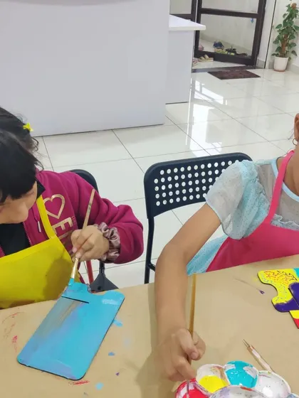 Two girls concentrating on painting their personalized desk calendars, a unique and practical art party activity.