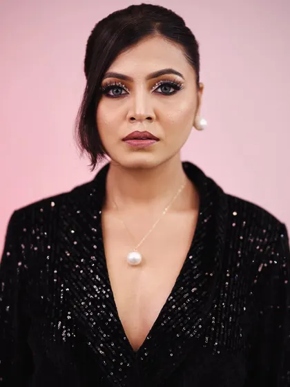 A powerful and chic party look. The sequined black blazer is paired with dramatic eye makeup and a simple pearl necklace, creating a look that is both edgy and elegant.