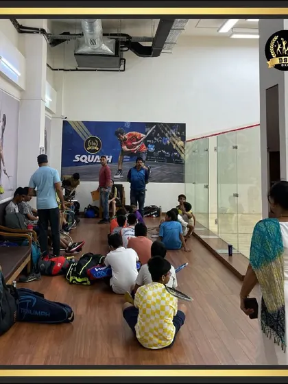 A group of young players listening intently to their coach before a squash session. We focus on providing quality coaching for all age groups in a supportive environment.