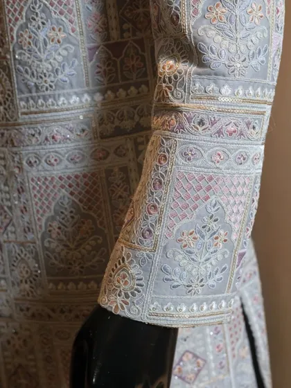 A close-up of the sleeve of our pastel-hued sherwani. You can see the fine threadwork and subtle sequin details that are woven into the geometric patterns, a testament to the skill of our artisans.