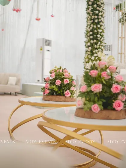A comfortable and stylish lounge area for the Nikah celebration. The setup includes modern gold-accented tables with pink rose centerpieces, providing an elegant space for guests to relax.