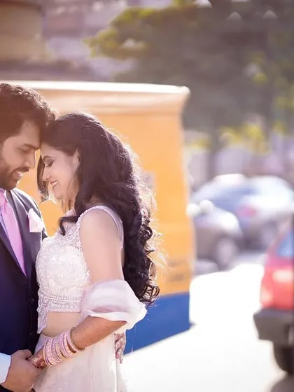 An intimate portrait with a unique backdrop of a yellow auto-rickshaw. The soft, backlit sunlight creates a romantic glow around the couple.