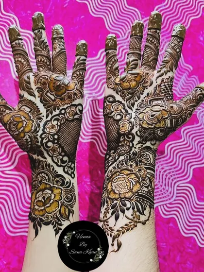A bold and artistic floral design with a unique vine pattern. The contrast against the pink background makes the henna art pop.