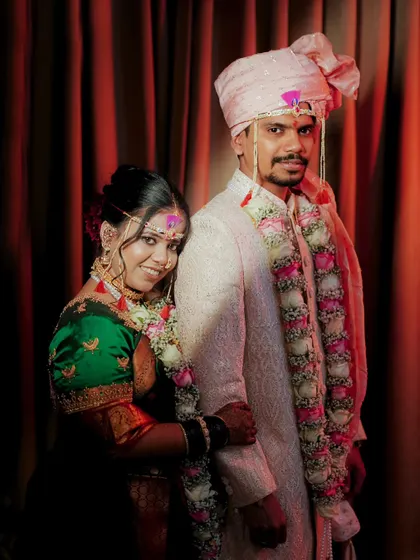 A formal portrait of the couple against a rich red backdrop, capturing a moment of quiet connection.