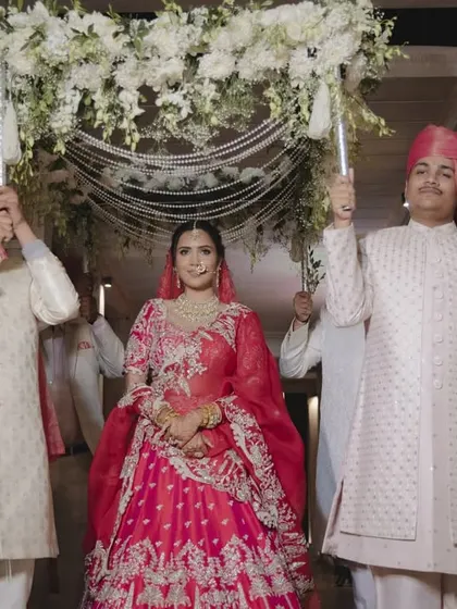 The bride makes her entrance under a beautiful 'phoolon ki chadar' made of white flowers and pearl strings. This traditional and elegant canopy adds a sense of grace and sanctity to her walk down the aisle.