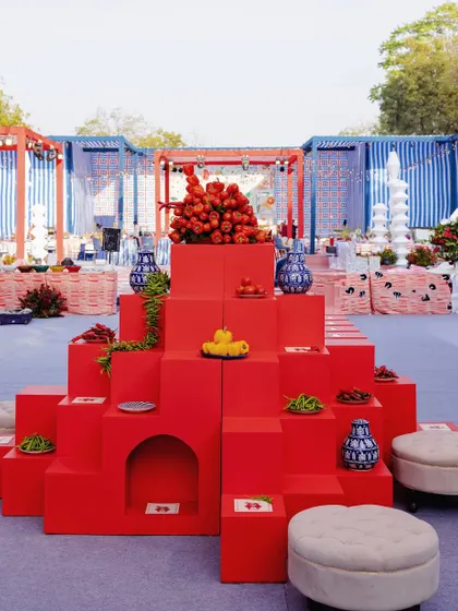 A unique and modern food display using a tiered structure of bright red blocks, adorned with blue and white porcelain vases.