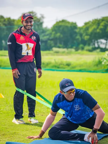Assisting a player with a resistance band stretch. Individual attention is crucial, even in a team setting, to address specific needs.