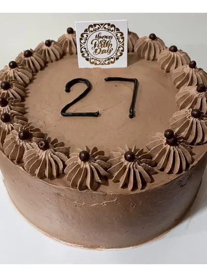 A classic Dutch truffle cake for a 27th birthday, decorated with chocolate cream swirls and crispy chocolate balls.