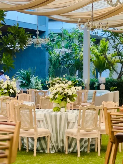 The dining area was set up like a botanical garden, with green and white striped tablecloths, elegant chairs, and large white floral centerpieces.