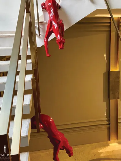 A detailed shot of the magnificent red panther sculptures. Their high-gloss finish provides a bold pop of color against the neutral tones of the staircase and walls.