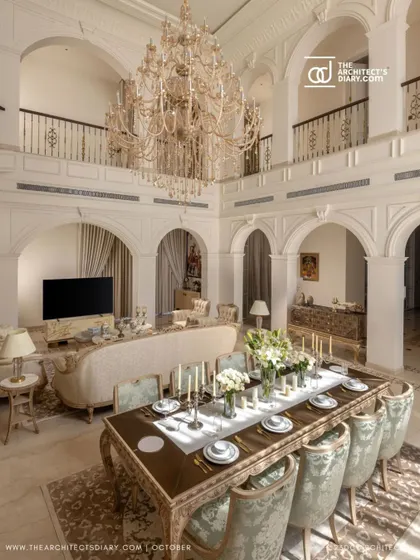 The double-height living and dining area of The Ivory Royale, as featured in The Architect's Diary. The space is designed for grand entertaining, with a massive chandelier presiding over an elegant, formally set dining table.