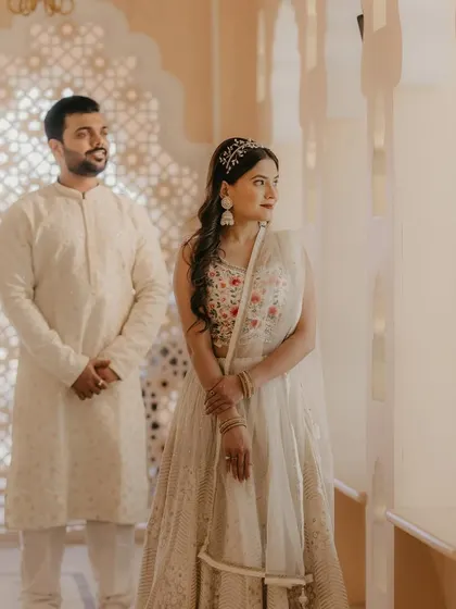 A serene pre-wedding shoot moment. The couple's coordinated white outfits are complemented by the bride's soft, natural makeup and an elegant hair accessory, creating a timeless and romantic image.
