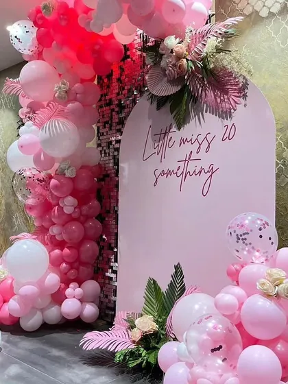 A chic and playful pink-themed setup for a "Little Miss 20-Something" birthday, featuring a sequin wall and tropical leaf accents.