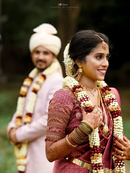 A candid shot of the bride with a beautiful smile, while the groom stands in the soft-focused background. This composition highlights the bride's joy on her wedding day.