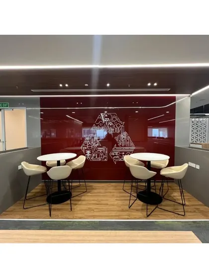 A breakout nook featuring two high-top tables against a bold red glass wall with custom graphics. This space provides an alternative work point for employees, promoting a dynamic and flexible office culture.