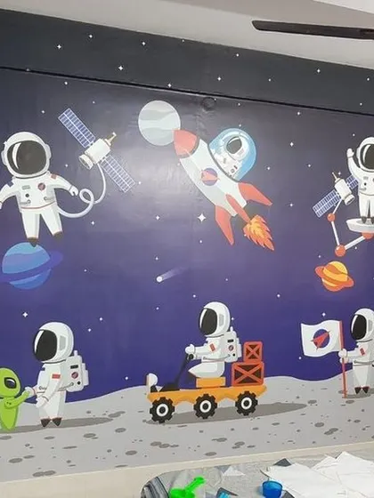 An outer space adventure unfolds on this bedroom wall, featuring cartoon astronauts, a friendly alien, and a moon rover. This is a great theme to inspire curiosity and a love for science.